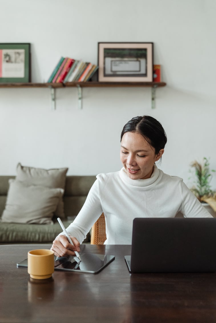 Young Asian female freelancer using gadgets while working at home